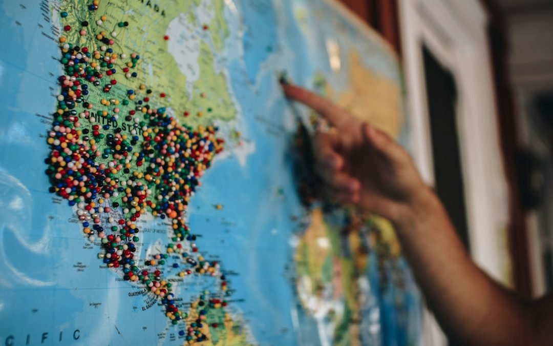 a person pointing at a map with pins on it